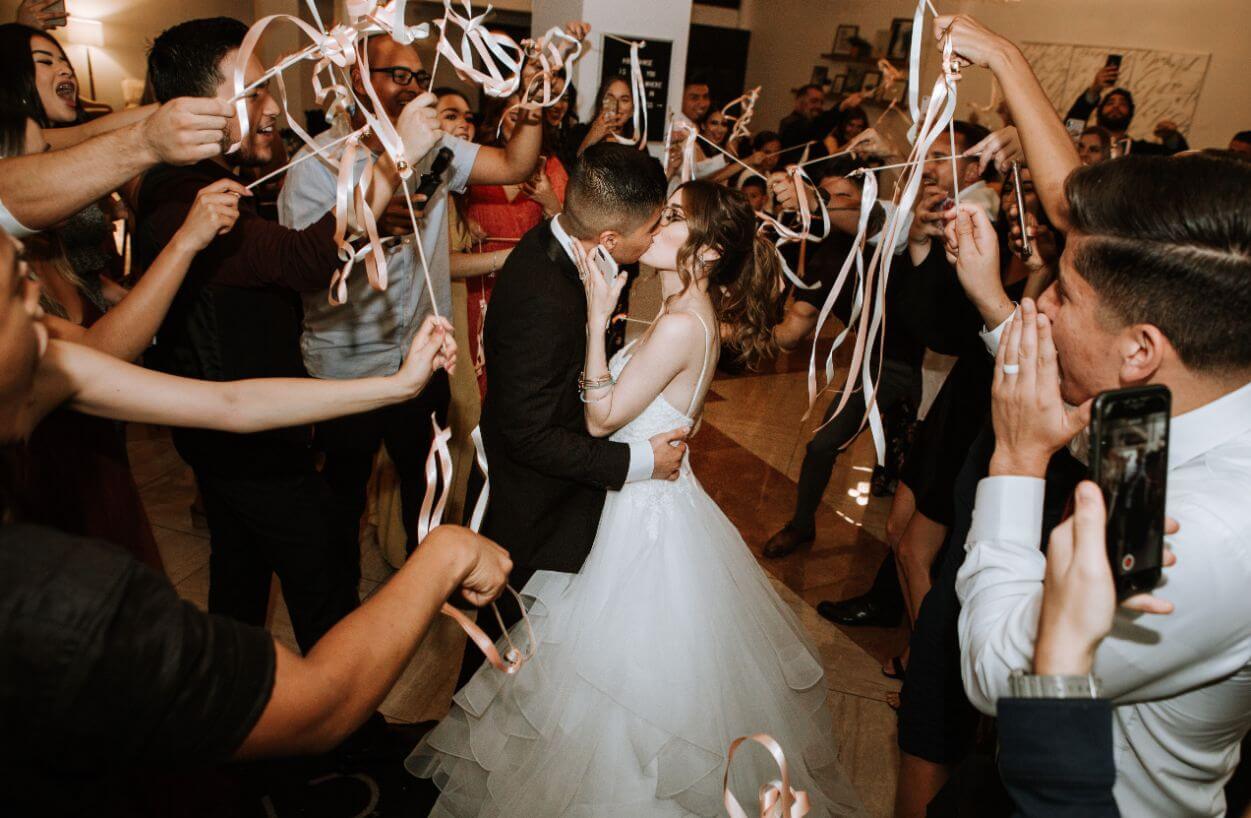 A bride and groom sharing a romantic kiss under confetti at their wedding reception, with the accompaniment of energetic music played by talented Chicago wedding DJs.