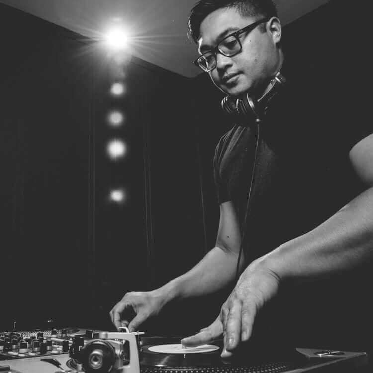 A black and white photo of a man djing in a dark room in Illinois.